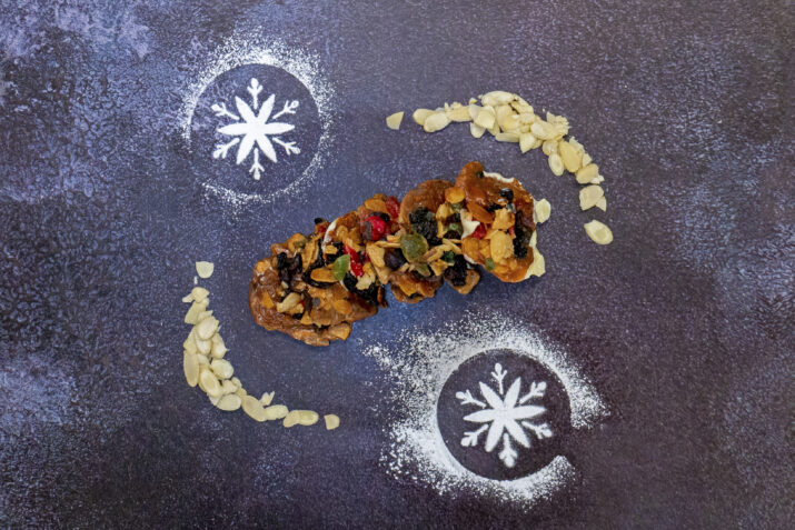 Florentines surrounded by icing sugar snowflakes and flaked almonds